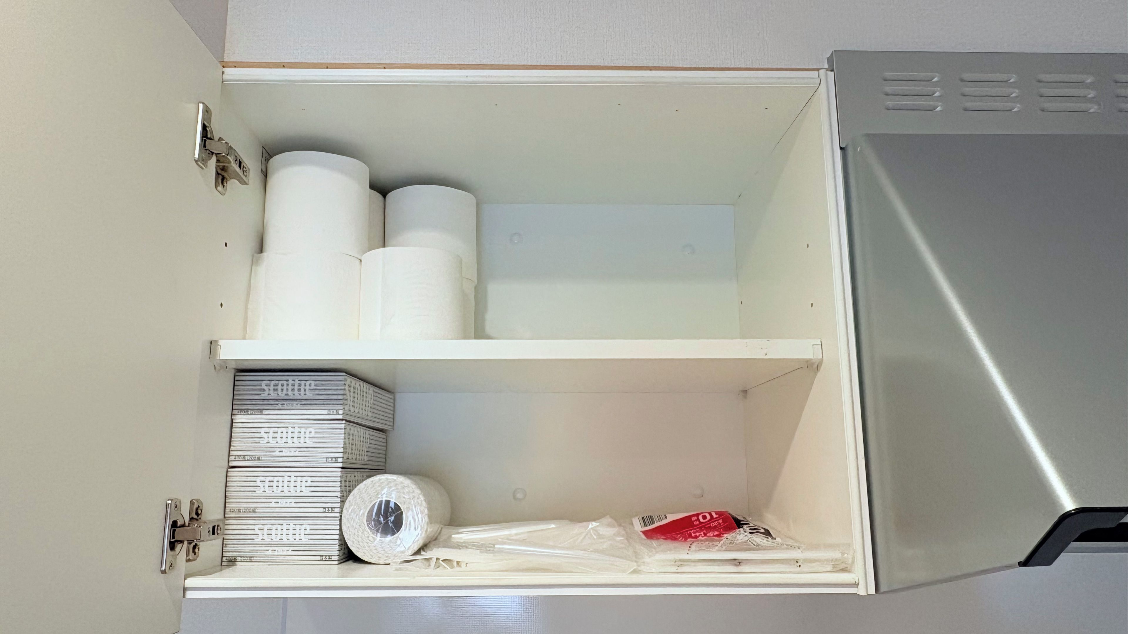 Ein Schrank mit Regalen, der Toilettenpapier, Küchenpapier und Kartons enthält.