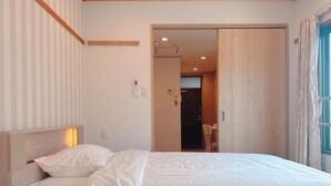 A hotel room with two beds, a wooden headboard, a sliding door leading to a bathroom, and a window with curtains.