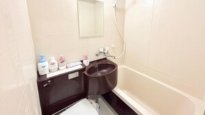 A bathroom with a white tiled wall, a black sink, and a shower.