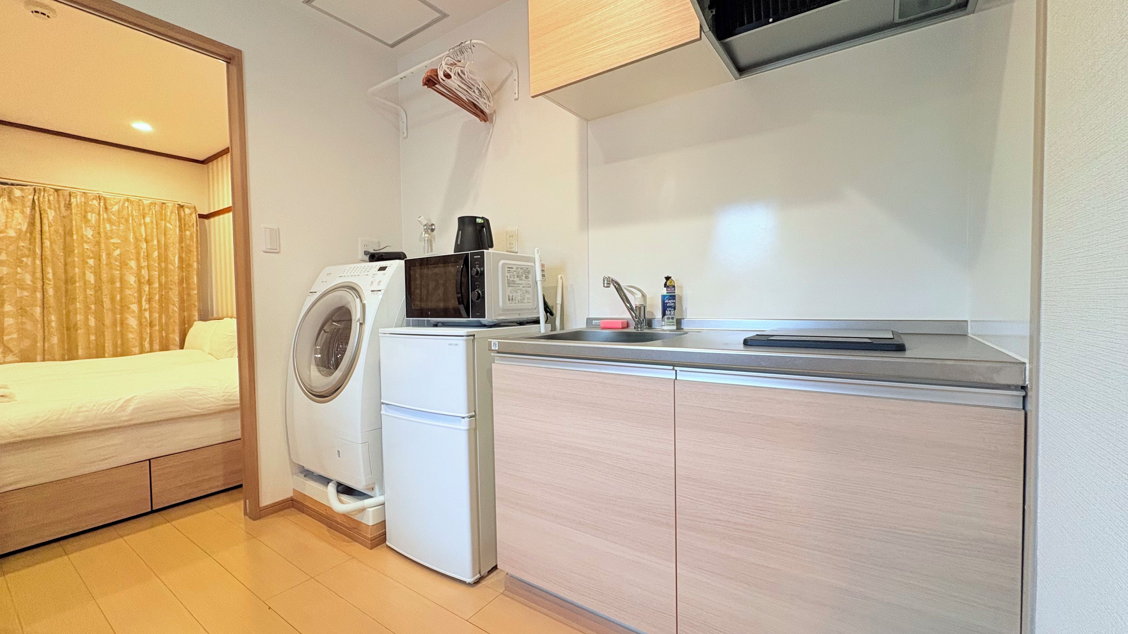 A compact kitchenette with a washing machine, microwave, and a small sink.