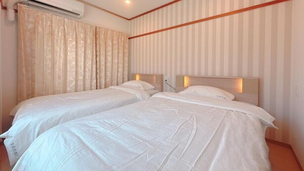 A hotel room with two beds, a striped wall, and an air conditioning unit.