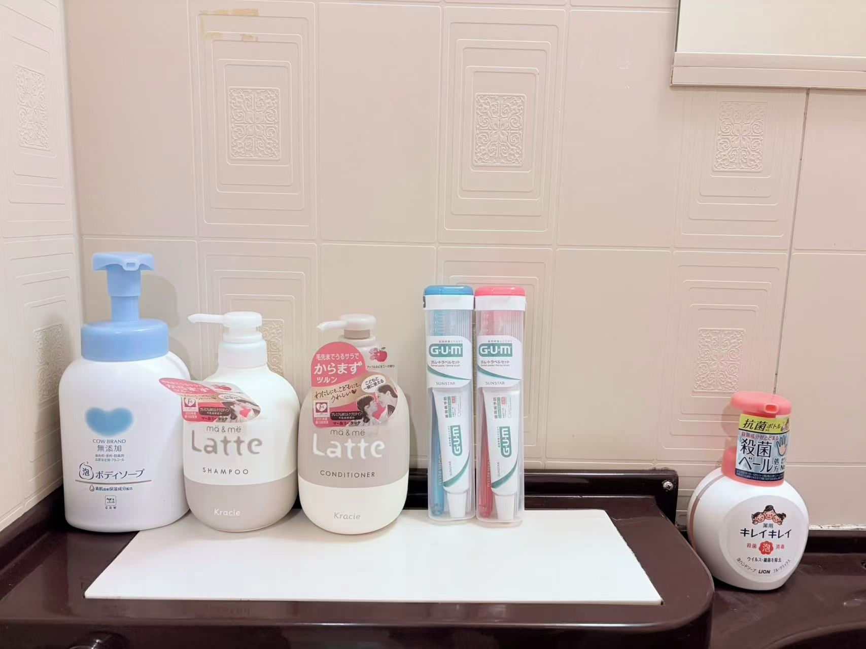 A bathroom counter with various toiletries including a shampoo bottle, conditioner, and toothbrushes.