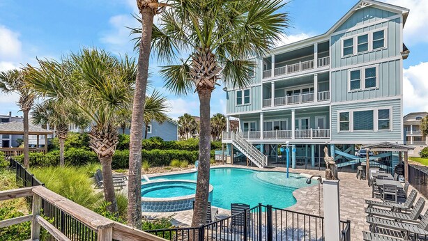 A multi-story building with a pool, surrounded by palm trees and a wooden deck. - Sea Y'all Soon - Oceanfront in Garden City Beach (Garden City Beach)