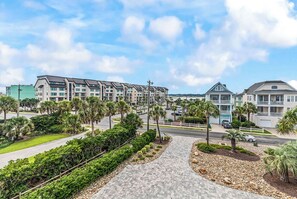 A residential area with multiple-story buildings, a paved walkway, and palm trees. - Sea Y'all Soon - Oceanfront in Garden City Beach (Garden City Beach)