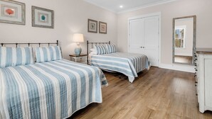 A bedroom with two beds, a nightstand, a lamp, and a door. - Sea Y'all Soon - Oceanfront in Garden City Beach (Garden City Beach)