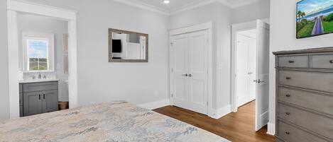 Quarto com cama, cômoda, espelho e porta que dá para outro ambiente.