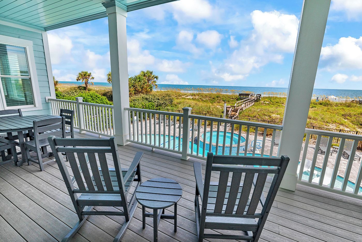 A covered outdoor area with a pool, seating, and a view of the beach.