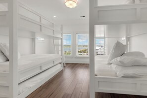 A room with bunk beds, wooden flooring, and large windows with blinds. - Coastal Point of View 10 Bedroom - Oceanfront in Garden City Beach (Garden City Beach)
