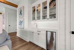 A kitchen with white cabinetry, a stainless steel refrigerator, and a built-in wine rack. - Coastal Point of View 10 Bedroom - Oceanfront in Garden City Beach (Garden City Beach)