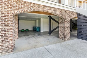 A garage with a brick archway, concrete floor, and a metal staircase leading to a second level. - Coastal Point of View 10 Bedroom - Oceanfront in Garden City Beach (Garden City Beach)