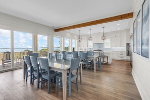 Eine geräumige Küche mit einer großen Kochinsel, Holzbalken an der Decke und Blick aufs Meer.