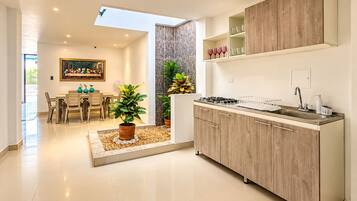 A modern kitchen with a skylight, a dining area with a painting, and a potted plant.