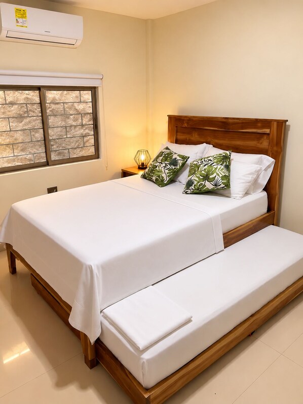 A bedroom with a bed, a nightstand, a lamp, and a window with frosted glass.