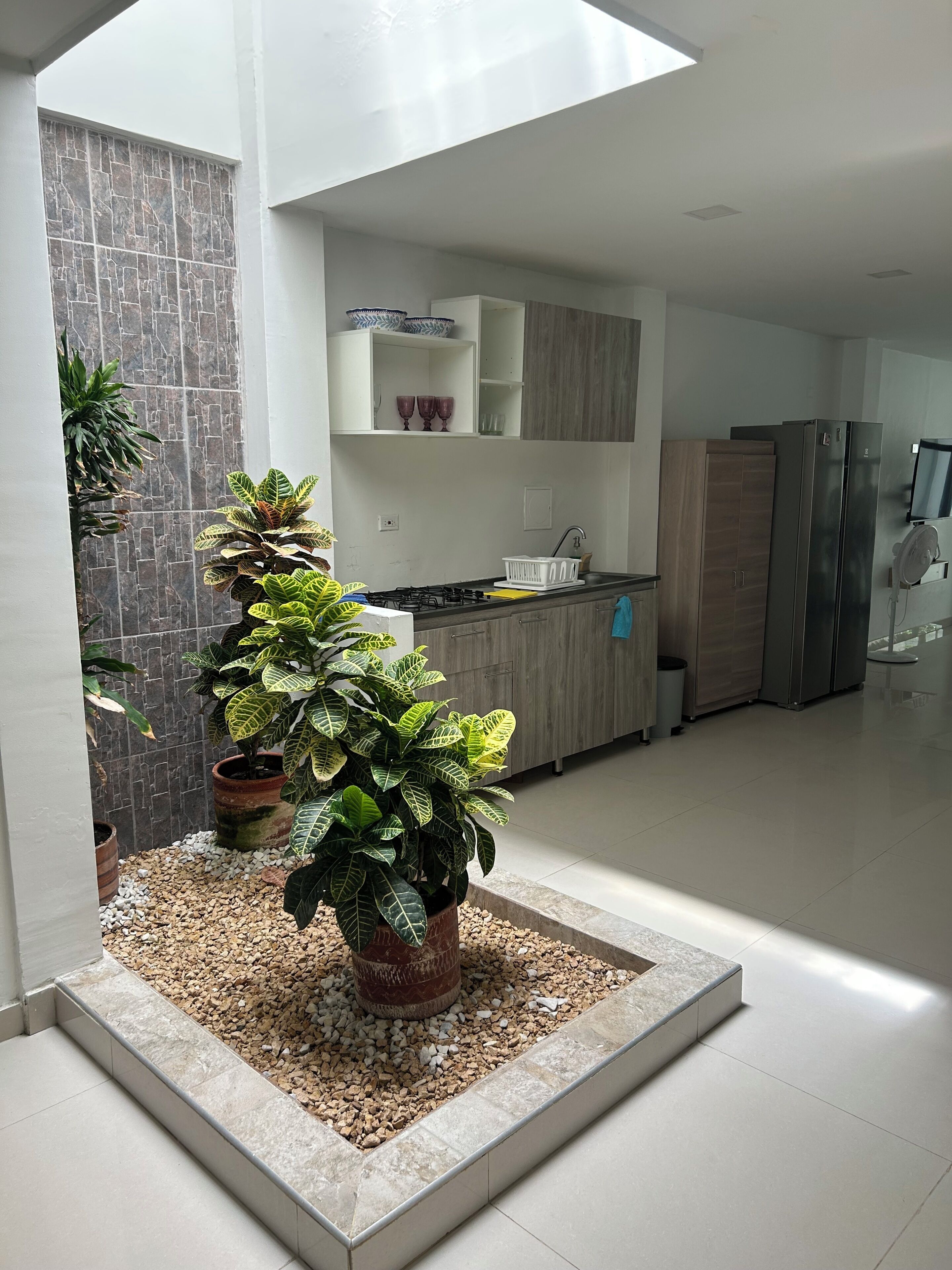 A modern kitchen with a built-in stove, wooden cabinets, and a large refrigerator.