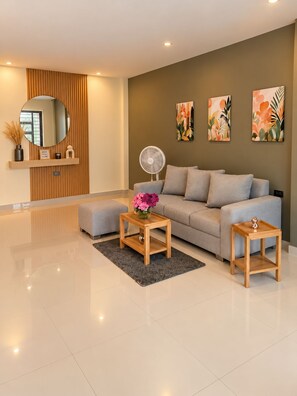 A modern living room with a sofa, two side tables, a mirror, and artwork on the wall.