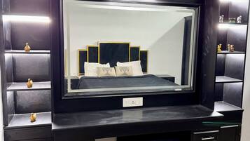 A black vanity with a large mirror, multiple drawers, and a shelf with decorative items.