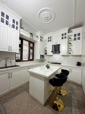 A modern kitchen with white cabinetry, a central island, and a black bar stool.