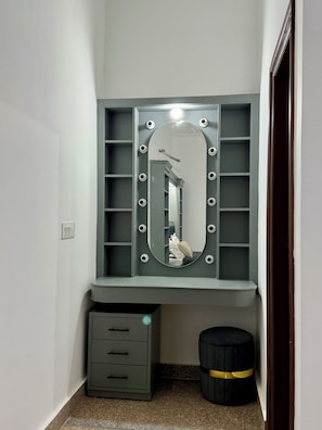 A bathroom with a vanity, a mirror, and a small stool.