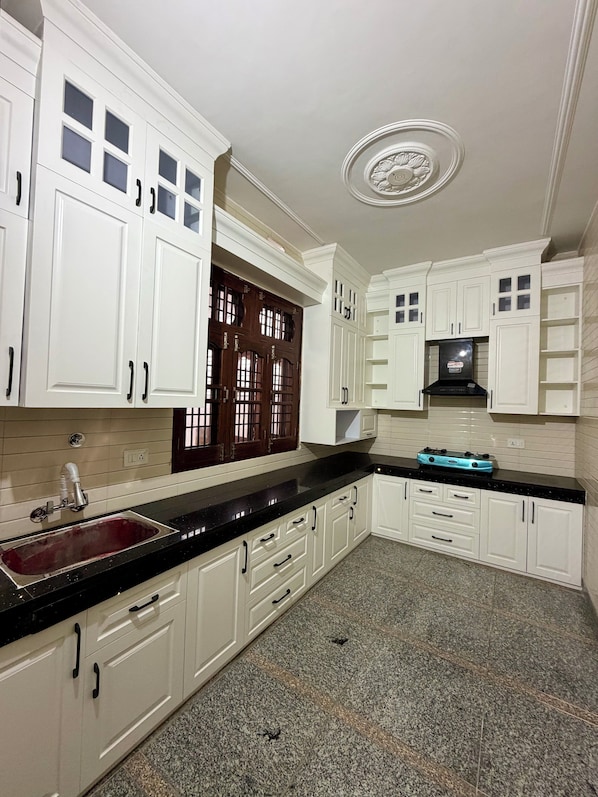 A kitchen with white cabinets, a black countertop, a stainless steel sink, and a blue stove.