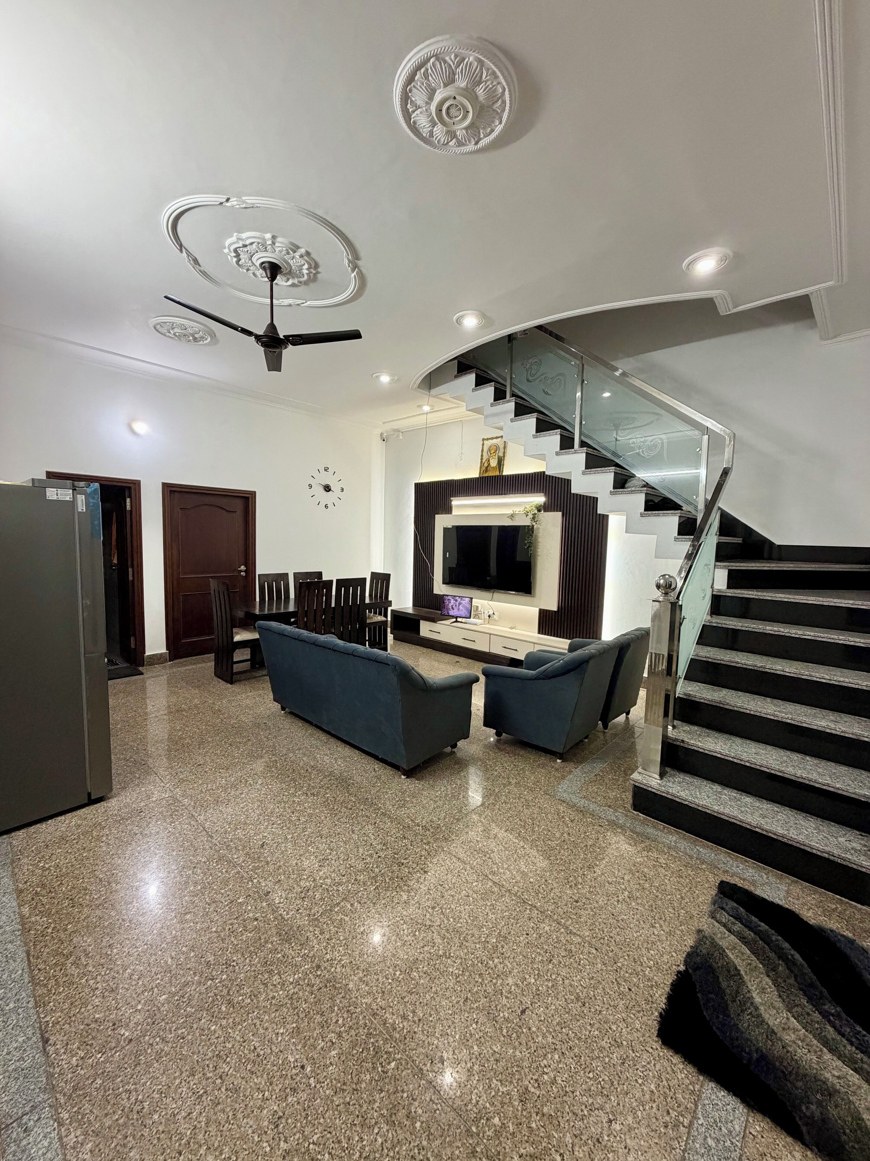 Un salon moderne doté d’un grand téléviseur, de canapés, d’un coin repas et d’un escalier.