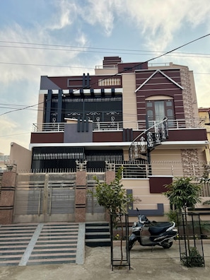 Une maison moderne à deux étages, dotée d’une entrée sécurisée par un portail, d’un escalier menant à l’étage supérieur et d’un scooter garé.