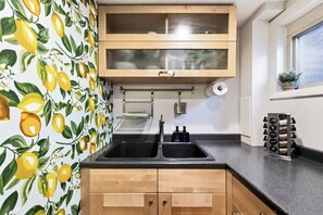A kitchen with a double sink, wooden cabinets, a window, and a lemon-themed wallpaper. - *New* Gorgeous Open Space, Perfect Location, Private Apartment! (Millcreek)