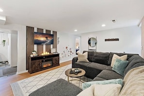 A modern living room with a sectional sofa, a flat-screen TV, a wooden entertainment unit, and a patterned rug. - *New* Gorgeous Space w/Big Rooms, Perfect Location - Apartment (Millcreek)