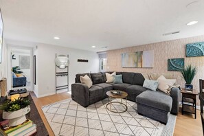 Un salon moderne avec un canapé d’angle, une table basse et un tapis à motifs.