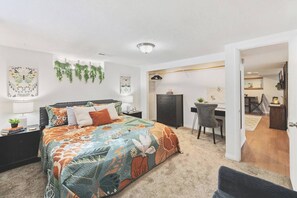 Une chambre à coucher avec un lit, un bureau et une chaise. Une porte donne accès à une autre pièce.