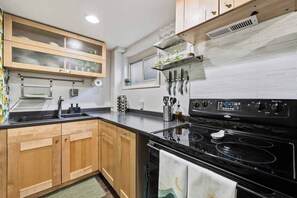 A modern kitchen with wooden cabinets, a black stove, and a window above the sink.