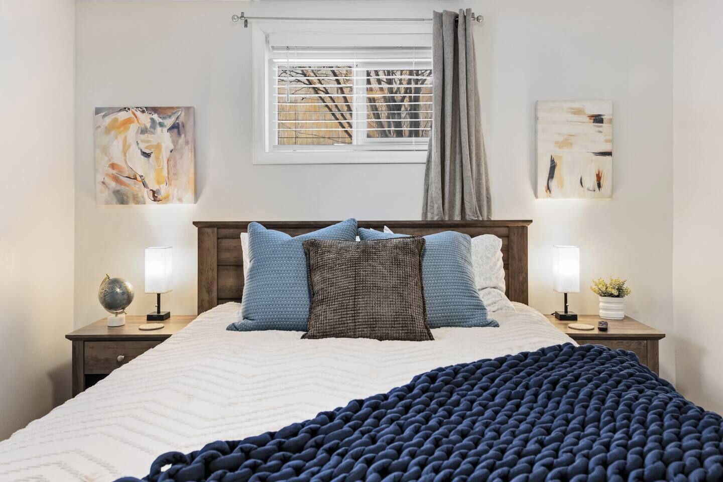 Una camera da letto con un letto, due comodini, una finestra con tende e decorazioni alle pareti.
