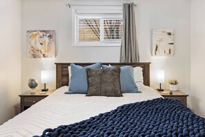 A bedroom with a bed, two bedside tables, a window with curtains, and wall art. - *New* Gorgeous Open Space, Perfect Location, Private Apartment! (Millcreek)