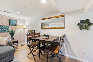 A dining area with a wooden table and chairs, a mirror above the table, and decorative wall art. - *New* Gorgeous Space w/Big Rooms, Perfect Location - Apartment (Millcreek)