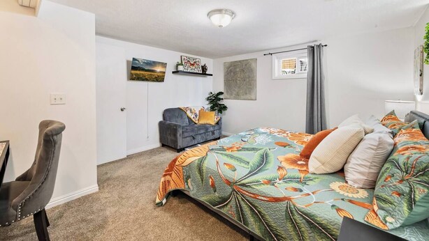 Ein Schlafzimmer mit Bett, Sessel, Schreibtisch und Fenster.
