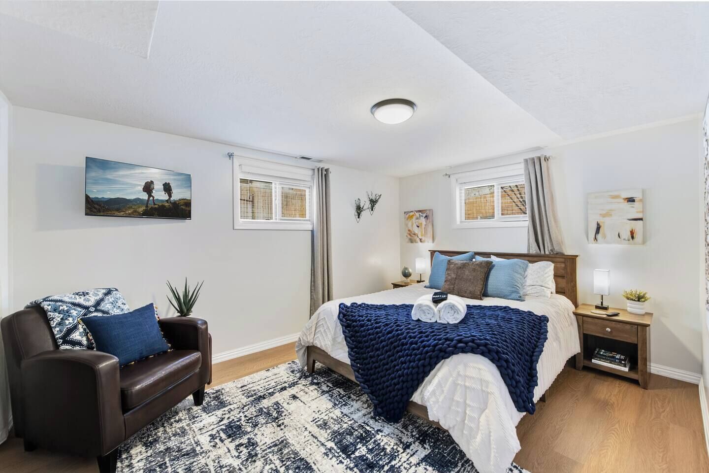 Ein Schlafzimmer mit Bett, Nachttisch, Lampe, Stuhl und Fenster.
