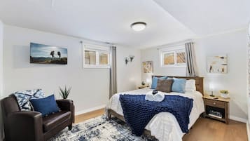 A bedroom with a bed, a nightstand, a lamp, a chair, and a window.