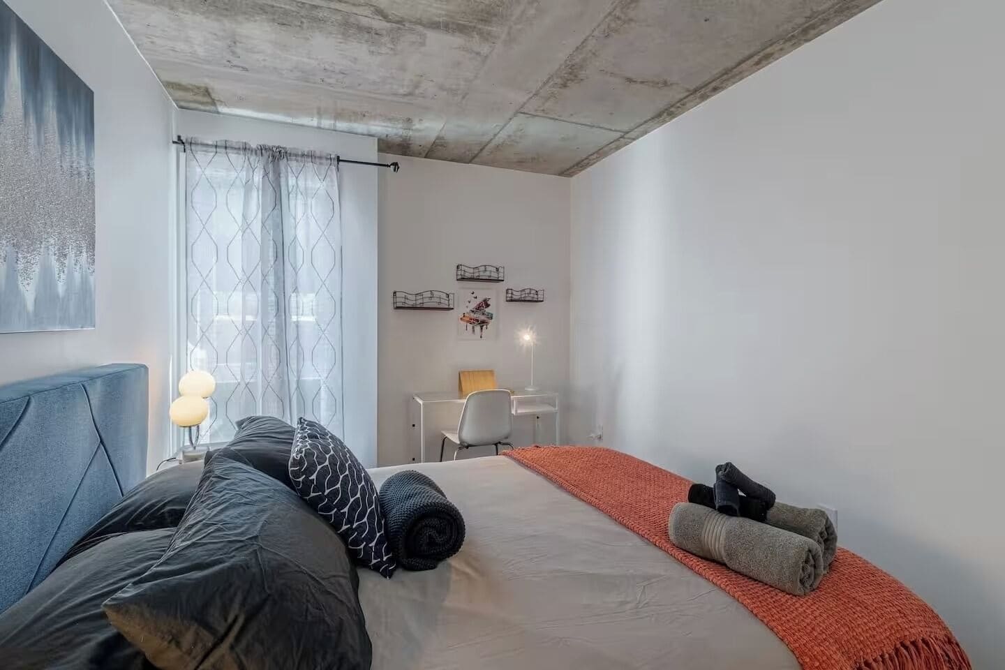 A bedroom with a bed, a desk, and a chair.