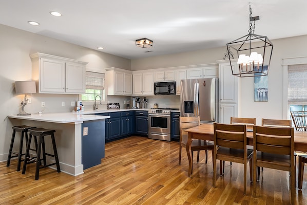 A modern kitchen with a central island, built-in appliances, and a dining area with wooden chairs.
