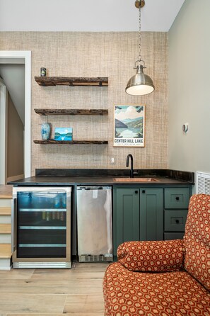 A kitchen with a built-in dishwasher, a hanging light fixture, and a framed picture of a lake.