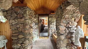 Un arco de piedra que da paso a un espacio interior de madera, con suelo de ladrillo y un abanico.