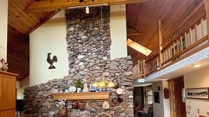 Un espace repas agrémenté d’un mur en pierre, de poutres en bois au plafond et d’un lustre.
