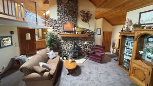 Un salon chaleureux avec une cheminée en pierre, un plafond en bois et un canapé confortable.
