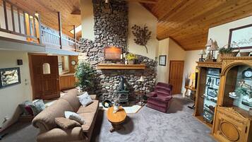 A cozy living room with a stone fireplace, a wooden ceiling, and a comfortable sofa.