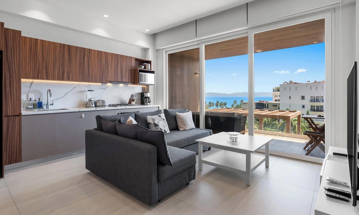 A modern living room with a sofa, a coffee table, and a view of the ocean.