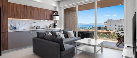 A modern living room with a sofa, a coffee table, and a view of the ocean.
