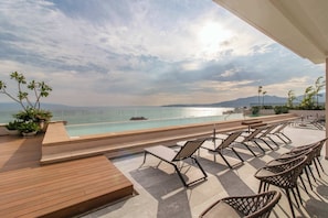 A poolside area with lounge chairs and a view of the sea. - Maralma Bucerías Retreat | Rooftop, Pool + Terrace (Bucerías)