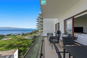 Ein Balkon mit Meerblick, einem Grill und Gartenmöbeln.