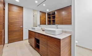 Ein modernes Badezimmer mit Holzschränken, zwei Waschbecken und einem großen Spiegel.