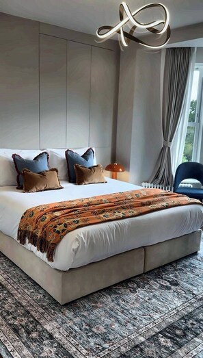 A modern bedroom with a large bed, a patterned throw blanket, and a unique ceiling light fixture.