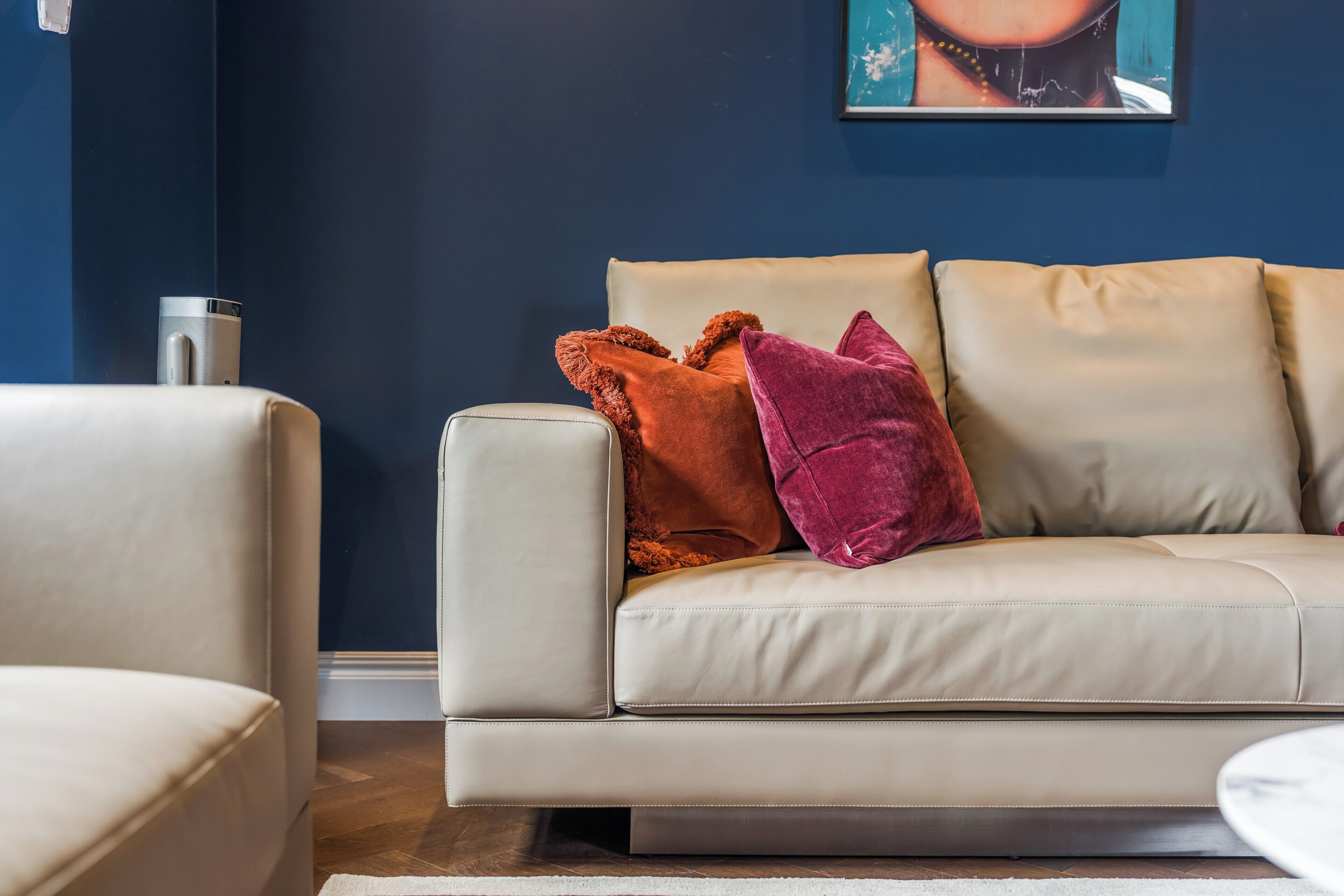 Una sala de estar moderna con un sofá color beige, una mesa de centro y un altavoz de pared.